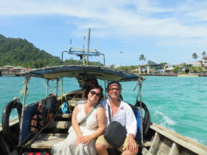 Ginger and Stanley sitting in a longtail boat with a Thai island in the background.