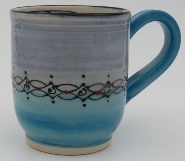 The Outside is Turquoise on the bottom and Pansy Blue on top. It has a band of black hand painted design with red dot accents. The inside is white and has a prayer flag design. Mug Measures approx. 4" tall x 5 1/2" wide to edge of handle and approx. 3 1/4" in diameter.